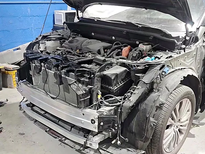 Toyota Venza negro con el frente destrozado y el motor expuesto antes de la reparación