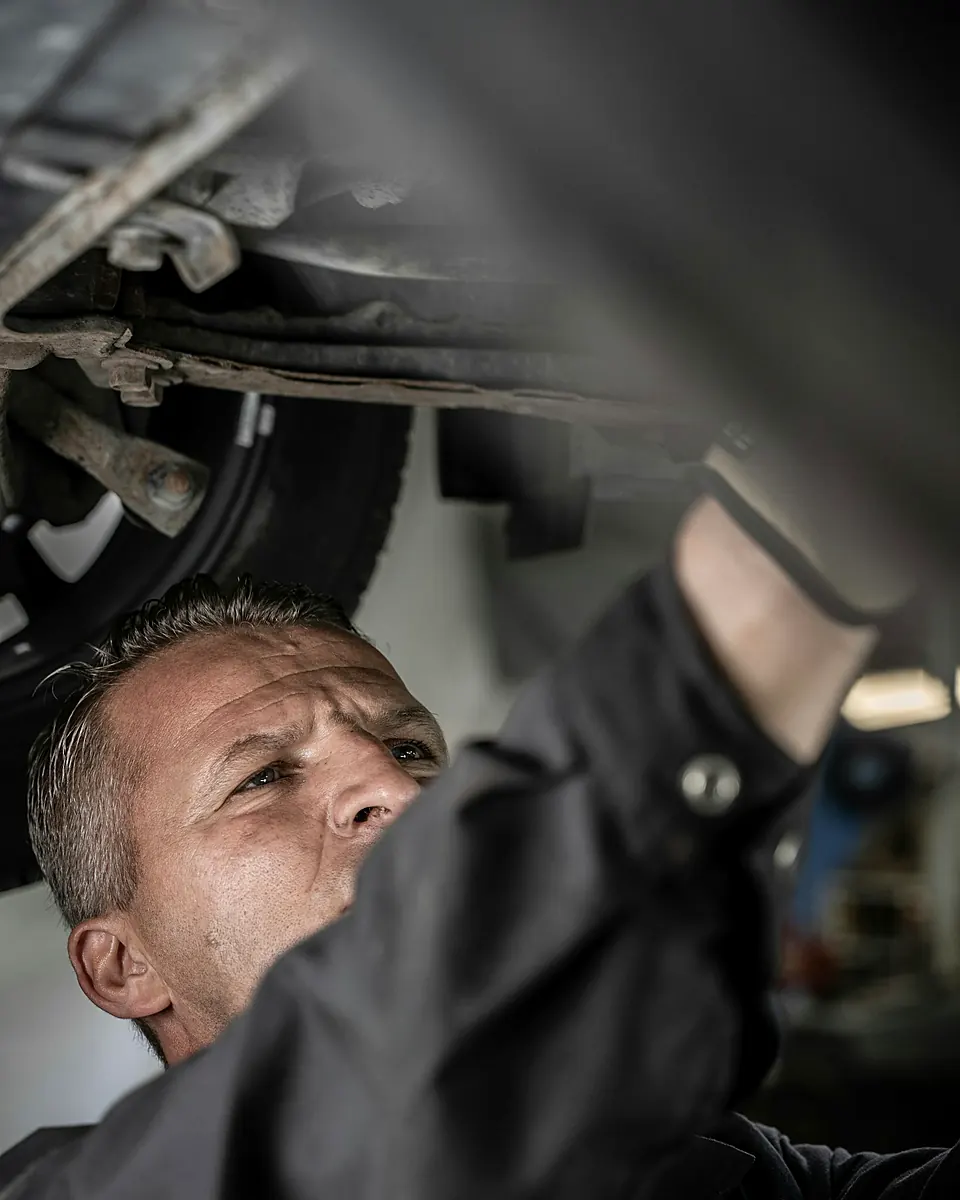 Técnico revisando el chasis por debajo de un carro levantado