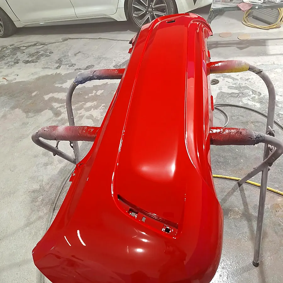 Bumper rojo recién pintado en la cabina de pintura de J&B