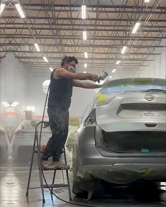 Pintor de J&B aplicando pintura a una SUV dentro de la cabina