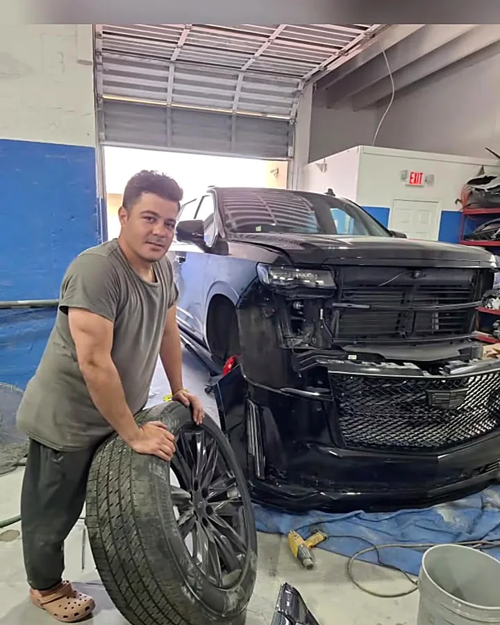 Técnico de J&B con una goma junto a un Cadillac Escalade en reparación